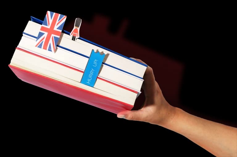A hand holding a stack of English-language books